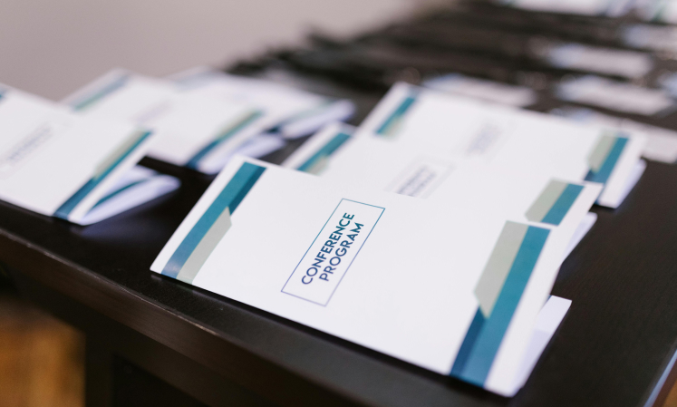 Stack of conference program booklets arranged on a table.