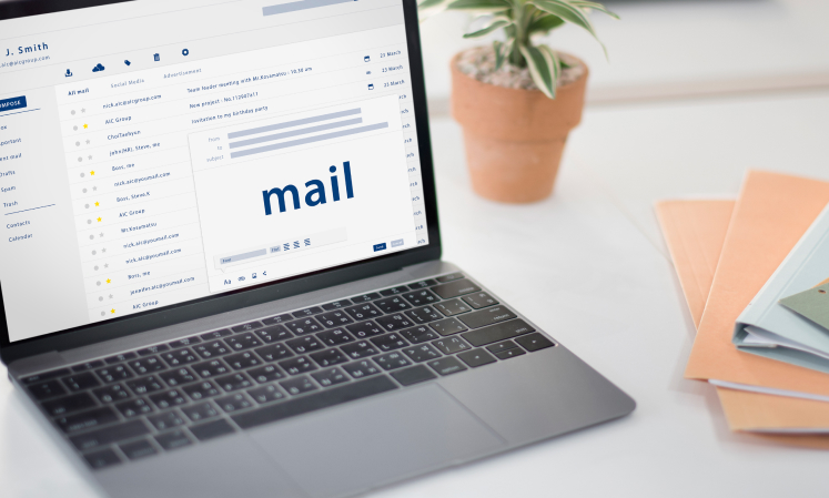 Open laptop on a desk displaying an email inbox, with folders and messages visible on the screen.